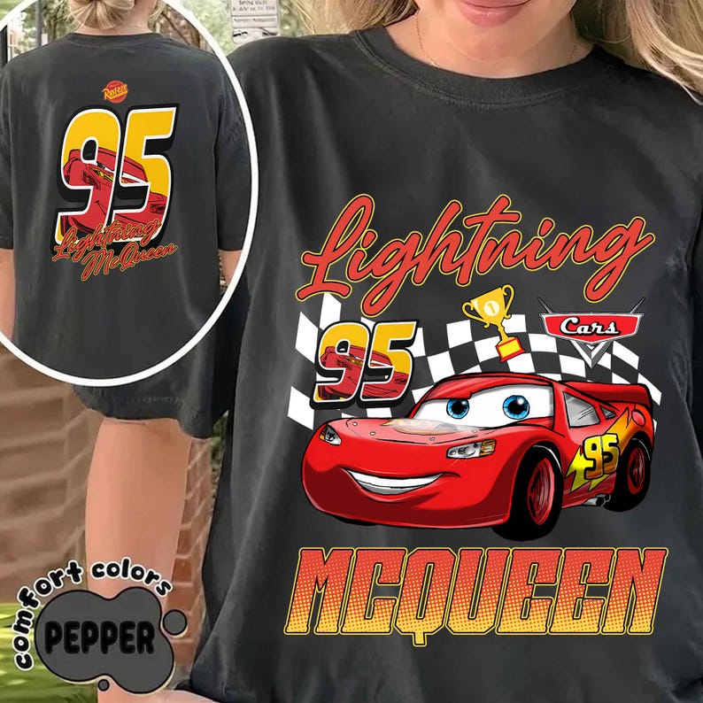 Może przedstawiać: Ciemnoszara koszulka z Lightning McQueen z filmu Auta. Grafika z przodu zawiera numer 95, szachownicę oraz słowa "Lightning" i "McQueen". Tył koszulki r&oacute;wnież przedstawia numer 95 i imię "Lightning McQueen".
