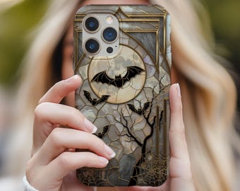 May include: A phone case featuring a Halloween design. The case has a stained-glass effect with a full moon, bats, and a bare tree. The color palette includes gray, black, and gold accents, creating a spooky aesthetic.
