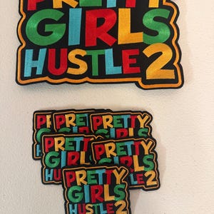 May include: Embroidered patches with the text "PRETTY GIRLS HUSTLE 2" in colorful letters on a black background. The patches are in a rectangular shape with a yellow border. Several patches are visible.