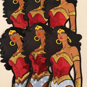 May include: Six embroidered patches featuring a female superhero with long black hair, a red and gold sequined bodice, and blue bottoms with white stars. The character wears a gold tiara with a red star, gold hoop earrings, and a gold necklace.