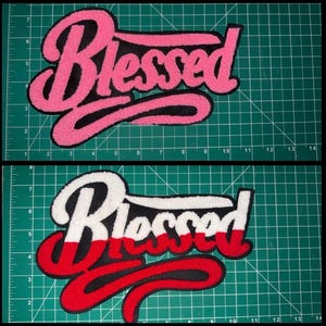 Puede incluir: Dos parches bordados con la palabra "Blessed". El parche superior es rosa con ribete negro, y el parche inferior es blanco con ribete rojo y negro. Los parches est&aacute;n sobre un fondo de cuadr&iacute;cula verde.
