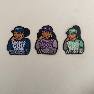 Puede incluir: Tres parches bordados que representan a una mujer con una gorra de béisbol con la palabra "FAITH". Cada parche tiene el texto "Chasing GOD not the WORLD" debajo de la imagen de la mujer. Los parches son azules, morados y verdes.