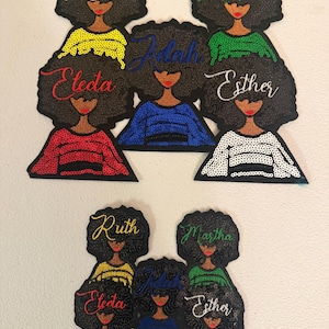 May include: Embroidered patches featuring stylized female figures with afros. Each patch has a different name embroidered in cursive: Ruth, Martha, Electa, Adah, and Esther. The figures wear tops in various colors, including yellow, green, red, blue, and white.