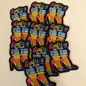 May include: A collection of embroidered patches featuring a pair of high-heeled shoes with rainbow-colored soles, blue denim cuffs, and a gold chain anklet with the word FAITH. The text Walking by Faith is embroidered in a colorful script above the shoes.