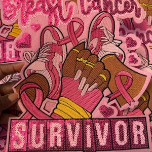 May include: Pink embroidered patches with the words "Breast Cancer" and "Survivor". The patches feature pink ribbons, running shoes, and a pair of hands. The word "Survivor" is spelled out in pink sequins.