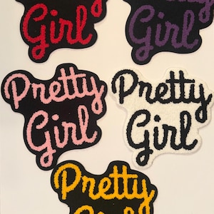 May include: Five embroidered patches with the words "Pretty Girl" in various colors. The patches are black with red, purple, pink, white, and yellow lettering. The patches have a fluffy, textured appearance.