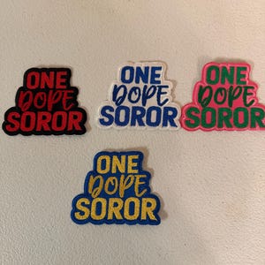 May include: Four embroidered patches with the words "ONE DOPE SOROR". The patches are in various color combinations: red and black, blue and white, pink and green, and yellow and blue.