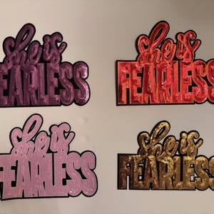 May include: A white ceramic mug with a black handle and the text "But First, Coffee" in a bold, black font. The mug is set against a blurred background, suggesting a cozy setting.