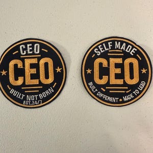 May include: Two black and gold embroidered patches with the word "CEO" in large gold letters. One patch reads "Built Not Born EST.24/7" and the other reads "Self Made Built Different Made to Lead". Both patches have a circular design.