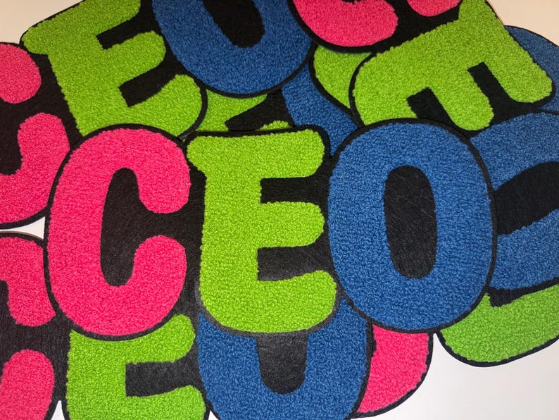 Peut inclure: Un ensemble d'&eacute;cussons color&eacute;s et textur&eacute;s &eacute;pelant "CEO". Les lettres sont en rose vif, vert et bleu, avec un support noir. Ces &eacute;cussons sont probablement destin&eacute;s aux v&ecirc;tements ou aux accessoires.