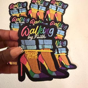 May include: A collection of embroidered patches featuring a pair of high-heeled shoes with light blue denim cuffs, a gold ankle chain with the word FAITH, and the text Walking by Faith in a multi-colored gradient font on a black background.
