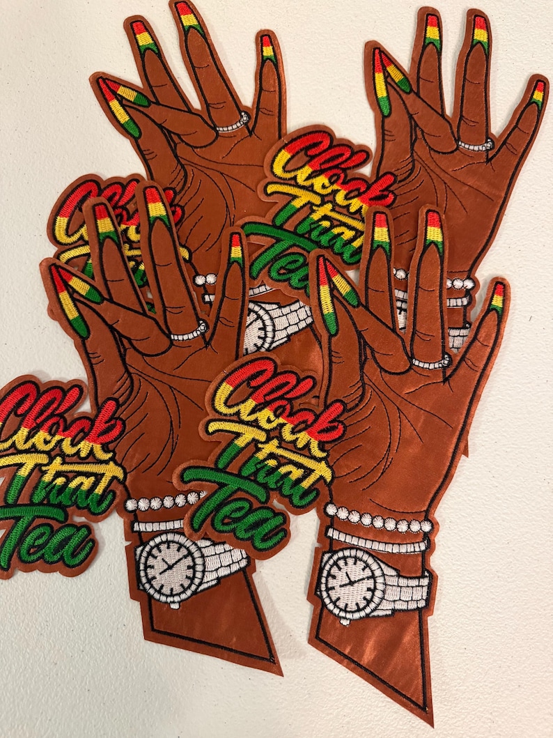 K&ouml;nnte beinhalten: Mehrere gestickte Aufn&auml;her mit einer braun get&ouml;nten Hand mit langen N&auml;geln, die in Rot, Gelb und Gr&uuml;n lackiert sind. Die Hand tr&auml;gt einen silbernen Ring, ein Perlenarmband und eine silberne Armbanduhr. Der Text Clock That Tea ist in Rot, Gelb und Gr&uuml;n gestickt.