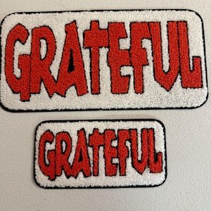 May include: Two rectangular patches with the word "GRATEFUL" in red, stylized, textured letters. The letters are on a white background with a black border. One patch is larger than the other.