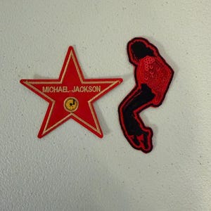 May include: Two embroidered patches: a red star-shaped patch with gold trim featuring the text MICHAEL JACKSON and a circular gold icon, and a black and red patch depicting a silhouette of a person in a dynamic dancing pose.