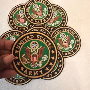 May include: A collection of circular embroidered patches featuring the United States Army emblem. Each patch has a green center with a brown eagle, a shield, and the text UNITED STATES ARMY in gold lettering on a black border with gold stars.