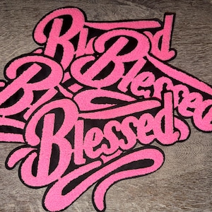 Puede incluir: Un parche bordado en rosa y negro con la palabra "Blessed" en cursiva. El parche tiene un fondo negro y un contorno rosa y difuso. La palabra "Blessed" se repite varias veces.