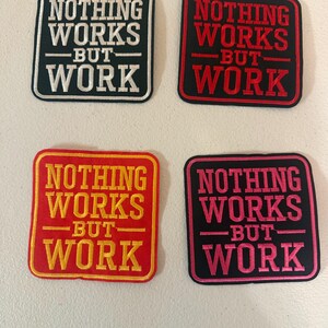 May include: Four embroidered patches with the text "NOTHING WORKS BUT WORK". The patches are square with rounded corners. The color combinations are black and white, black and red, red and yellow, and black and pink.