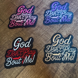 May include: Four embroidered patches with the phrase "God Don't Play Bout Me!" in various color schemes. The patches have a black border and feature the text in pink, purple, red, and gold, with a decorative font.