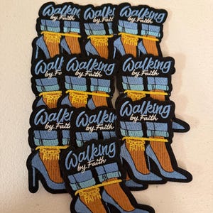 May include: A collection of embroidered patches featuring a pair of light blue high-heeled shoes with cuffed blue jeans, a yellow ankle chain with the word FAITH, and the text Walking by Faith in light blue script lettering on a black background.