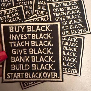 May include: Black fabric patches with white embroidered text. The patches read "BUY BLACK. INVEST BLACK. TEACH BLACK. GIVE BLACK. BANK BLACK. BUILD BLACK. START BLACK OVER."