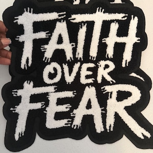 May include: A black and white tufted textile patch featuring the text FAITH OVER FEAR in a distressed, brush-stroke style font. The white lettering is set against a solid black background with a thick, contoured black border surrounding the design.