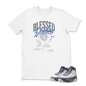 May include: White t-shirt with the text "BLESSED DREAM" above a rose illustration. Below the shirt are a pair of white, black, and blue sneakers.