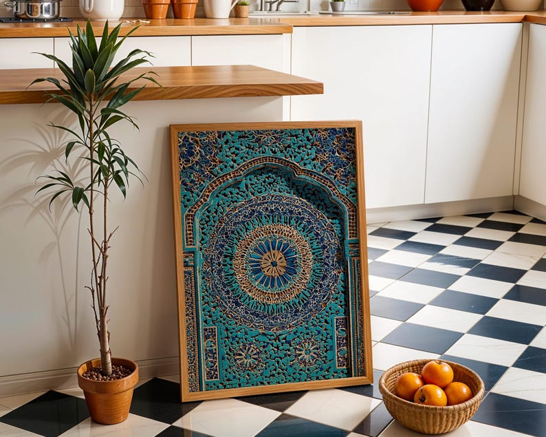 May include: A framed, intricately carved wooden panel with a teal and gold mandala design. The panel is leaning against a white wall, next to a potted plant and a basket of oranges. The frame is made of light-coloured wood.