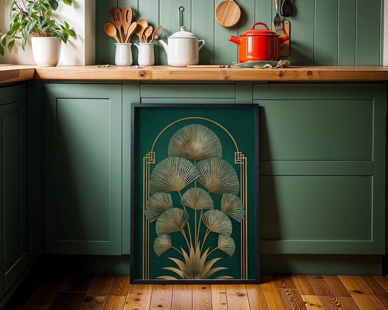 May include: A framed art print featuring a gold botanical design on a dark green background. The artwork has a black frame and is displayed in a kitchen setting with green cabinets and wooden countertops.