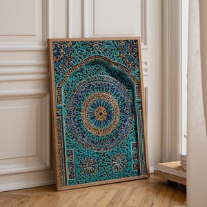 Op de afbeelding: Een ingelijst, ingewikkeld gesneden houten paneel met een turquoise, blauw en goud mandala-ontwerp. Het kunstwerk heeft gedetailleerde patronen en een centraal cirkelvormig motief, geplaatst in een rechthoekige lijst. Het staat tegen een witte muur en houten vloer.