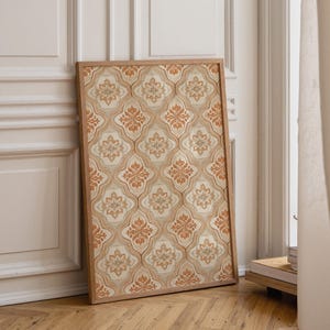 May include: A rectangular framed wall art piece featuring a repeating pattern of orange and cream-coloured quatrefoil shapes. Each shape contains a central floral motif with intricate symmetrical details, enclosed within a light brown wooden frame.