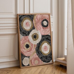 May include: A framed abstract art print featuring a mosaic design of overlapping circles. The circles are in shades of pink, black, white, and gold, creating a textured effect. The artwork is displayed in a wooden frame.