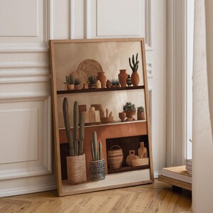 Op de afbeelding: Een ingelijste muurkunstprint met een display op meerdere niveaus. De illustratie toont diverse terracotta-kleurig aardewerk, gevlochten manden en cactussen in potten in tinten bruin, beige en donkergroen, gerangschikt in een gestructureerde compositie.