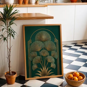May include: A framed art print featuring a gold fan design on a dark green background. The artwork is in a wooden frame and leans against a wall. A potted plant and a basket of oranges are in the foreground. The floor has a black and white checkered pattern.