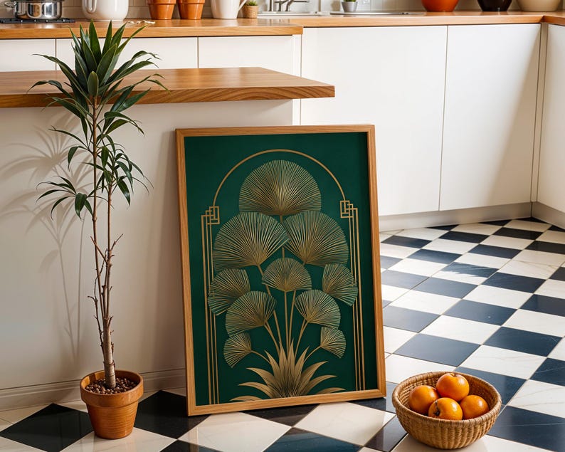 May include: A framed art print featuring a gold fan design on a dark green background. The artwork is in a wooden frame and leans against a wall. A potted plant and a basket of oranges are in the foreground. The floor has a black and white checkered pattern.