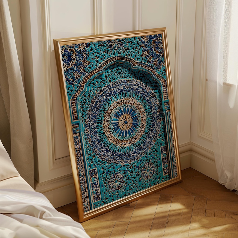 May include: A framed, ornate wall art piece with a gold-coloured frame. The artwork features a detailed, carved design in shades of teal, blue, and gold. The intricate pattern includes floral and geometric elements, creating a layered, three-dimensional effect. The artwork is leaning against a white wall.
