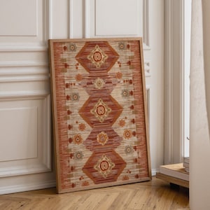 Puede incluir: Una pieza de arte mural rectangular enmarcada que presenta una disposición vertical de formas de diamante y motivos florales repetitivos en tonos naranja quemado, crema y verde salvia, dentro de un marco de madera clara con acabado texturizado.