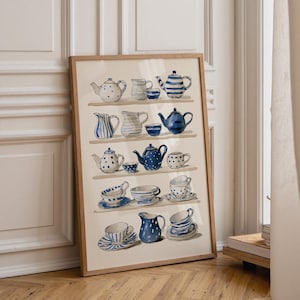 May include: A framed wall art print featuring a watercolour illustration of various blue and white ceramic teapots, pitchers, cups, and saucers arranged on five horizontal shelves against a light cream background with visible brushstrokes.