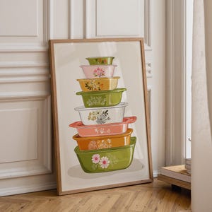 Peut inclure: Une impression d'art encadrée représentant une pile verticale de huit récipients de cuisine rectangulaires de tailles et de couleurs variées, dont vert, rose, jaune, blanc et orange, chacun orné de motifs floraux et d'illustrations au trait.