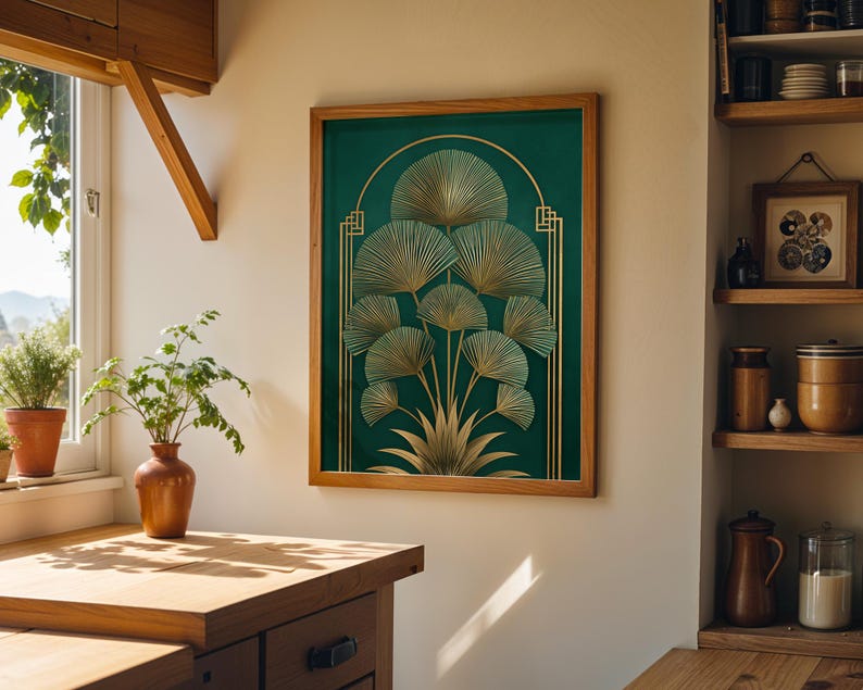 May include: A framed art print featuring a botanical design with gold fan-shaped leaves on a dark green background. The artwork is in a wooden frame and hangs on a white wall. The image is in a well-lit room with a wooden countertop and a window.