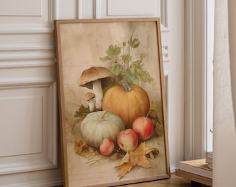 May include: A framed wall art print featuring a still life illustration of a large orange pumpkin, a smaller pale green pumpkin, three red apples, and two brown mushrooms nestled among scattered dried autumn leaves and green foliage.