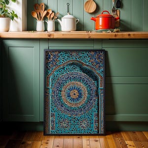 May include: A framed, intricately carved wooden panel with a teal and gold mandala design. The artwork features a central circular pattern and an arched top, displayed against a green kitchen cabinet.