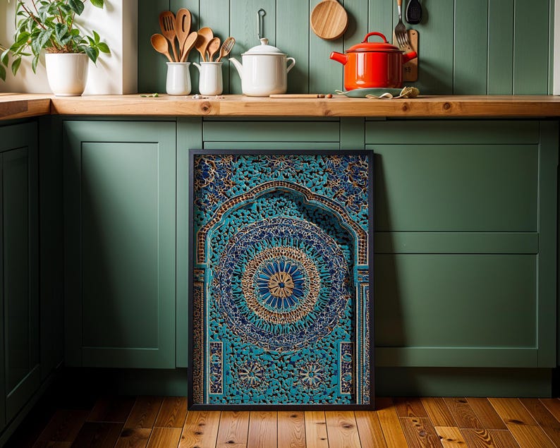 May include: A framed, intricately carved wooden panel with a teal and gold mandala design. The artwork features a central circular pattern and an arched top, displayed against a green kitchen cabinet.