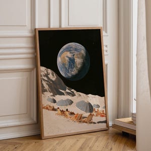 May include: A framed art print featuring a surreal collage of a sandy lunar landscape with people lounging on beach chairs under striped umbrellas, while the blue and white Earth hangs prominently in the dark black sky above the cratered surface.