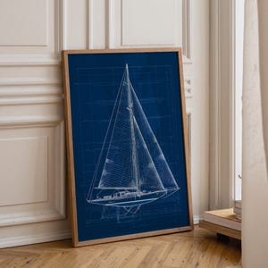 Puede incluir: Una lámina de arte enmarcada que presenta una ilustración técnica en blanco de un velero sobre un fondo azul oscuro. El diseño del velero incluye detalles de aparejos, mástiles y velas, sobre una cuadrícula de finas líneas blancas.