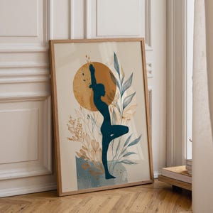 Puede incluir: Una lámina de arte enmarcada que muestra la silueta de color verde azulado oscuro de una persona en postura de yoga. El diseño incluye un gran círculo amarillo mostaza y elementos botánicos dibujados con líneas en azul y oro sobre un fondo beige.
