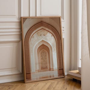 May include: A rectangular framed wall art print featuring a perspective view of a series of nested, pointed arches. The architectural design displays intricate, light-colored floral carvings and geometric patterns in shades of beige and cream.