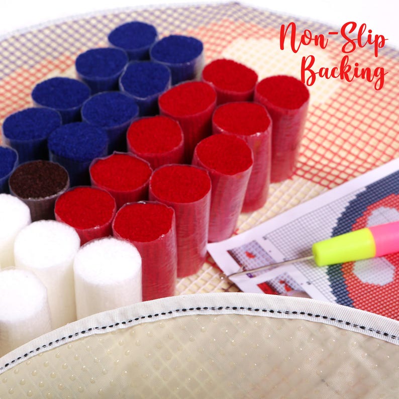 May include: A craft kit with red, white, and blue yarn cylinders arranged on a grid, resembling a flag. The words "Non-Slip Backing" are in the upper right corner. A needle and a punch tool are also visible.