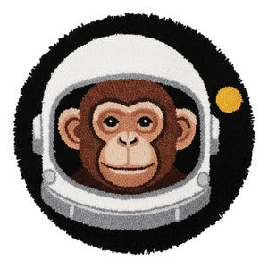 May include: A round rug featuring a monkey wearing an astronaut helmet. The monkey's face is brown, with a smiling expression. The helmet is white and gray, set against a black background with a yellow dot. The rug has a black, textured border.