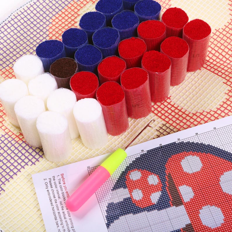 May include: A craft kit with bundles of red, white, blue, and brown yarn, a pink and yellow punch needle, and a printed pattern. The pattern includes instructions and a grid for a rug or wall hanging project.