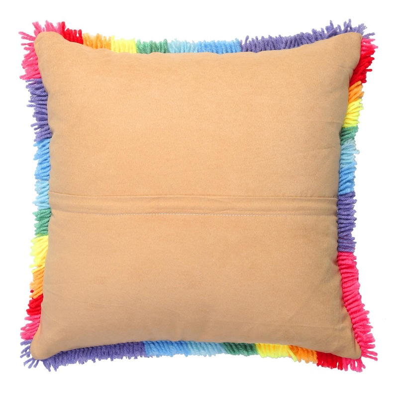 Puede incluir: Un coj&iacute;n cuadrado con un centro de tela color canela s&oacute;lido y una costura horizontal en el medio. Los bordes del coj&iacute;n est&aacute;n terminados con un borde de flecos grueso y texturizado que presenta una vibrante secuencia de colores.